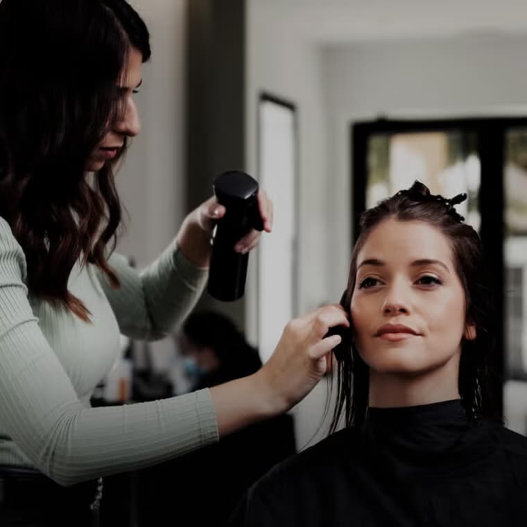 Haarstylist die het haar van een klant doet in een chique salon, die salonservices beschikbaar op Salony uitbeeldt.