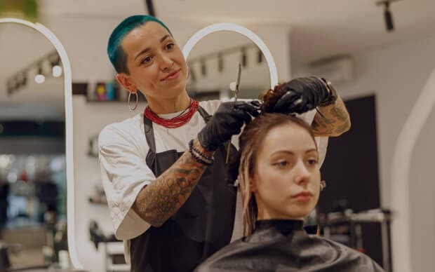 Haarstylist die het haar van een klant knipt met een schaar in een salon