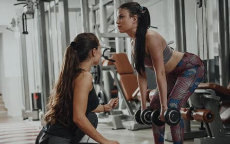 Personal trainer die een klant begeleidt tijdens een fitnesstraining in een sportschool