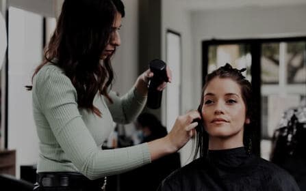 Haarstylist die het haar van een klant knipt met een schaar in een salon
