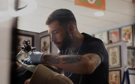 Tatoeëerder die de arm van een klant ininkt in een moderne studio